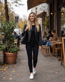 Mulher caminhando na calçada com a jaqueta preta (imagem criada com IA)