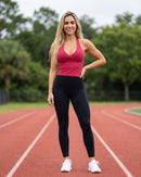 Modelo com a regata vermelha e legging preta numa pista de corrida (imagem criada com IA)